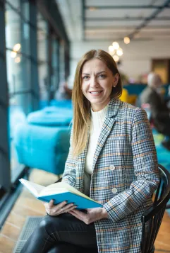 Poznaj nas | Uniwersytet WSB Merito Bydgoszcz: studentka z książką w dłoniach siedzi na krześle