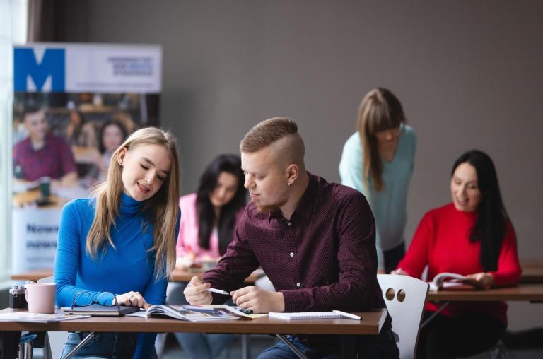 Strefa studenta | Uniwersytet WSB Merito Bydgoszcz: dwóch studentów w sali wykładowej przy biurku z książkami