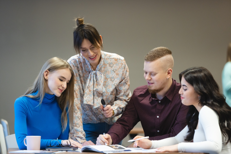 Trening menedżerski, studia podyplomowe: 4 studentów WSB Merito w Bydgoszczy siedzi przy stole i pracuje nad projektem
