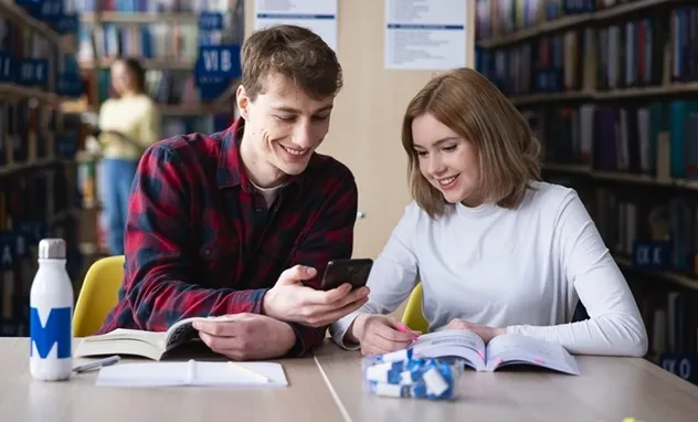 41. Czwartki Social Media 16 kwietnia! [GALERIA ZDJĘĆ] | Aktualności | Uniwersytet WSB Merito Bydgoszcz: student pokazuje studentce ciekawą rzecz w telefonie