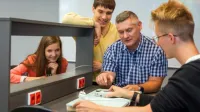 Inteligentne systemy logistyczne | Studia I stopnia w Chorzowie | Uniwersytet WSB Merito Chorzów: studenci omawiający użycie urządzenia