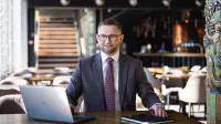MBA HR | Studia MBA w Chorzowie | Uniwersytet WSB Merito Chorzów: Uczestnik studiów MBA pracuje przy stole z laptopem i notesem- Uniwersytet WSB Merito Chorzów