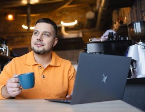 Cyfrowy uniwersytet | Uniwersytet WSB Merito Chorzów: student z kawą i laptopem