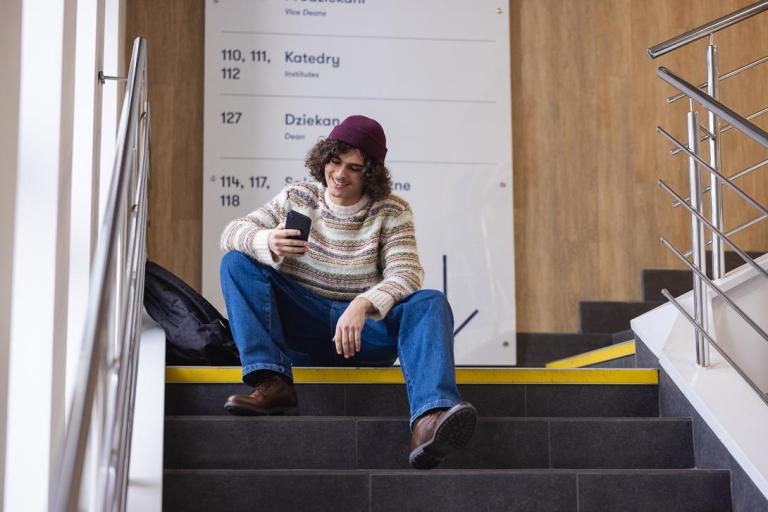 Cyfrowy uniwersytet | Uniwersytet WSB Merito Chorzów: student siedzący na korytarzu uczelni