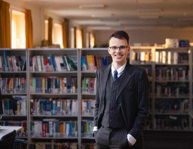 Logistyka i spedycja międzynarodowa | Studia I stopnia w Chorzowie | Uniwersytet WSB Merito Chorzów: Student stojący w bibliotece