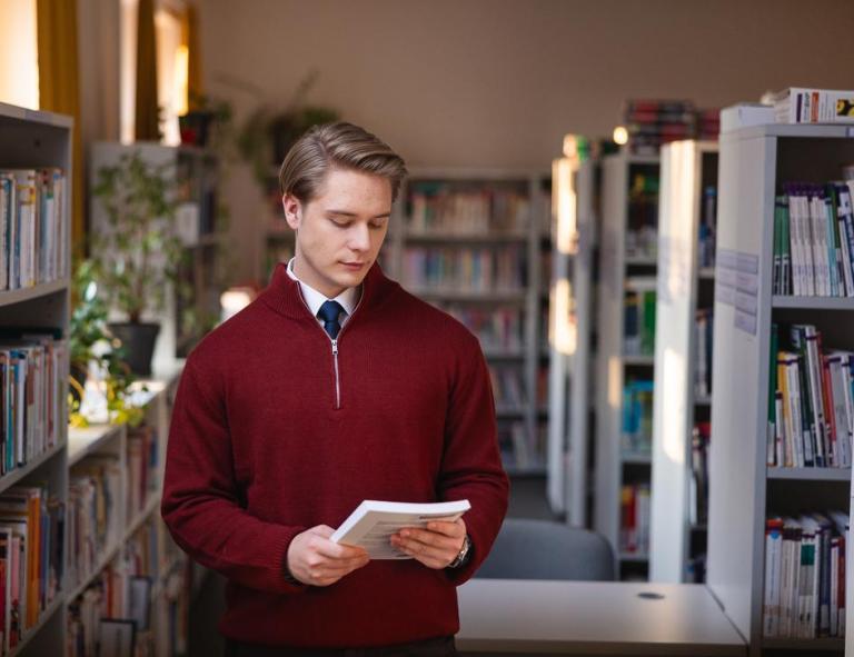 Szkoły | Uniwersytet WSB Merito Chorzów: Student przeglądający książkę w bibliotece
