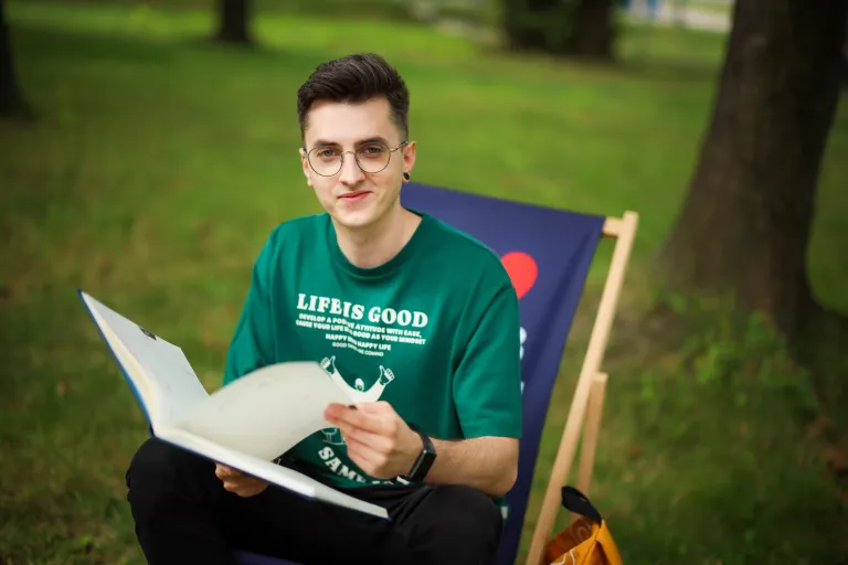 Finanse i rachunkowość | Studia II stopnia ze studiami podyplomowymi w Chorzowie | Uniwersytet WSB Merito Chorzów: Student WSB MErito siedzi na leżaku w parku i przegląda notatnik