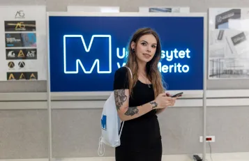 Our values | WSB Merito Bydgoszcz University: studentka z telefonem w ręku na korytarzu uczelni