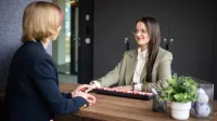 Administracja publiczna | Studia I stopnia w Gdańsku | Uniwersytet WSB Merito w Gdańsku: Dwie kobiety siedzą przy biurku naprzeciwko siebie i załatwiają sprawy administracyjne