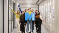Kreowanie treści w mediach cyfrowych | Studia II stopnia ze studiami podyplomowymi  | Uniwersytet WSB Merito w Gdańsku: Zdjęcie grupowe studentów na korytarzu z sygnetem "M"