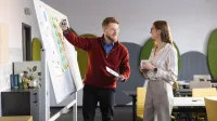Specjalista kadr i płac z elementami technik coachingu | Studia II stopnia ze studiami podyplomowymi  | Uniwersytet WSB Merito w Gdańsku: Wykładowca tłumaczy studentce temat przy tablicy
