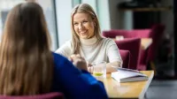 Zarządzanie zasobami ludzkimi | Studia II stopnia w Gdańsku | Uniwersytet WSB Merito w Gdańsku: Rozmowa studentek w przestrzeni kawiarni 