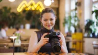 E-marketing | Studia I stopnia w Gdańsku | Uniwersytet WSB Merito w Gdańsku: Studentka w kawiarni trzymająca w ręku aparat fotograficzny