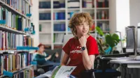 Inżynieria oprogramowania dla technologii kosmicznych | Studia I stopnia w Gdańsku | Uniwersytet WSB Merito w Gdańsku: Studentka czyta książkę w bibliotece