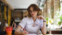 Terapia pedagogiczna z elementami integracji sensorycznej | Studia II stopnia ze studiami podyplomowymi  | Uniwersytet WSB Merito w Gdańsku: Studentka przy notatkach i napoju w kawiarni 