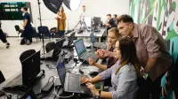 Technologie sieciowe | Studia I stopnia w Gdańsku | Uniwersytet WSB Merito w Gdańsku: Studenci w studio z komputerami, lampami i grafiką na ścianie