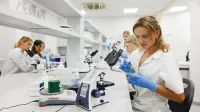 Podologia w praktyce | Studia podyplomowe w Gdańsku | Uniwersytet WSB Merito w Gdańsku: Studentka podczas warsztatów w laboratorium z mikroskopami