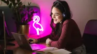 Smart Marketing | Studia II stopnia ze studiami podyplomowymi  | Uniwersytet WSB Merito w Gdańsku: Studentka przy laptopie i świetle neonu z pelikana