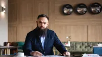 Psychologia polityki i komunikacja w kampaniach wyborczych | Studia podyplomowe w Gdańsku | Uniwersytet WSB Merito w Gdańsku: Mężczyzna z lekkim zarostem i w ciemnej marynarce