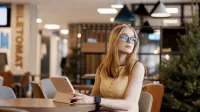 Bankowość 4.0 i finanse cyfrowe | Studia I stopnia w Gdańsku | Uniwersytet WSB Merito w Gdańsku: Studentka z tabletem przy biurku w holu 