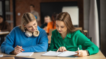 Psychologia w marketingu | Studia I stopnia w Gdańsku | Uniwersytet WSB Merito w Gdańsku: dwie dziewczyny siedzą przy biurku i pochylają się nad zeszytami