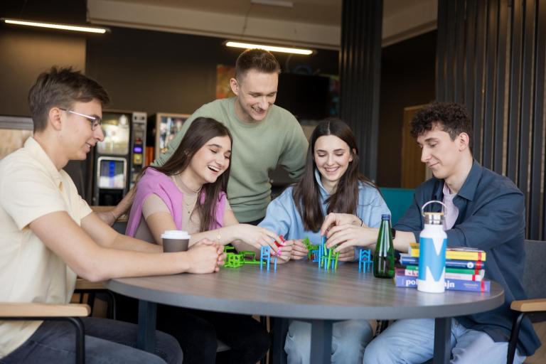 Logistyka - studia inżynierskie | Studia I stopnia w Gdańsku | Uniwersytet WSB Merito w Gdańsku: Studenci siedzą na przerwie i układają konstrukcję z zabawkowych krzesełek