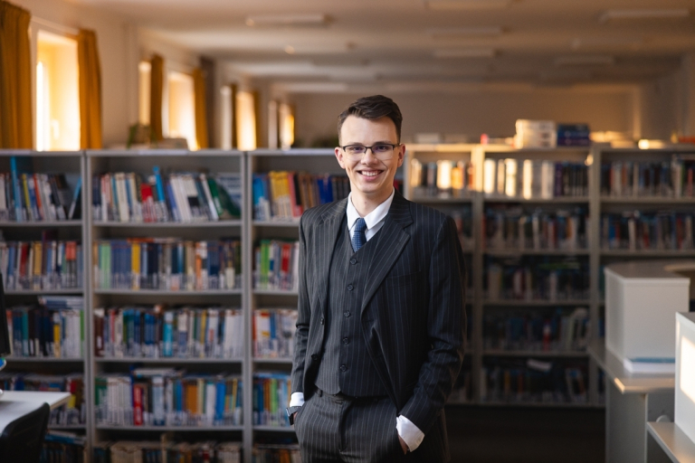 Rachunkowość i controlling | Studia II stopnia ze studiami podyplomowymi  | Uniwersytet WSB Merito w Gdańsku: Student w bibliotece ubrany w garnitur 