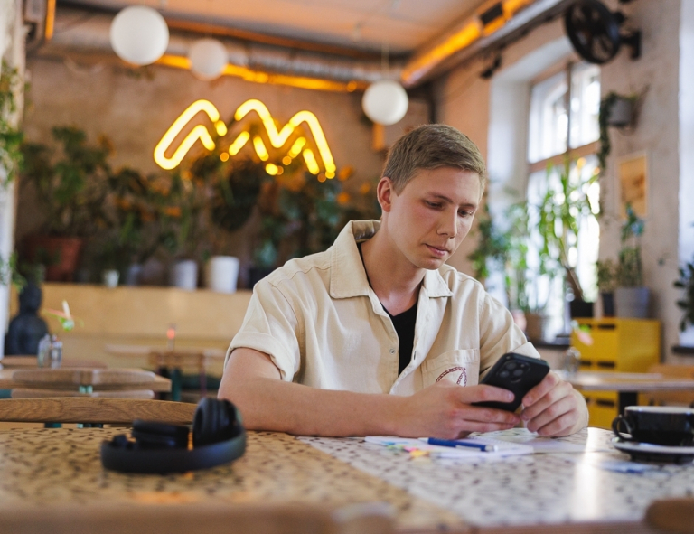 Copywriting | Studia II stopnia ze studiami podyplomowymi  | Uniwersytet WSB Merito w Gdańsku: Student przy telefonie w kawiarni 