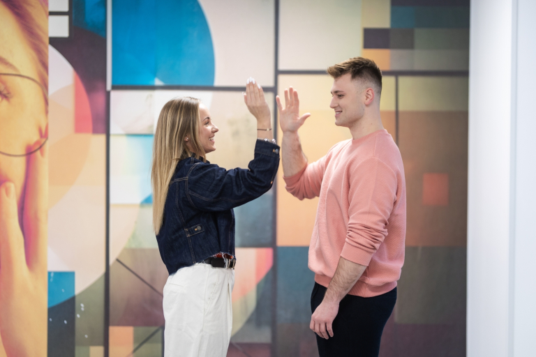 Film marketingowy w e-commerce | Studia I stopnia w Gdańsku | Uniwersytet WSB Merito w Gdańsku: Studentka i student przybijają sobie piątkę na korytarzu uczelni