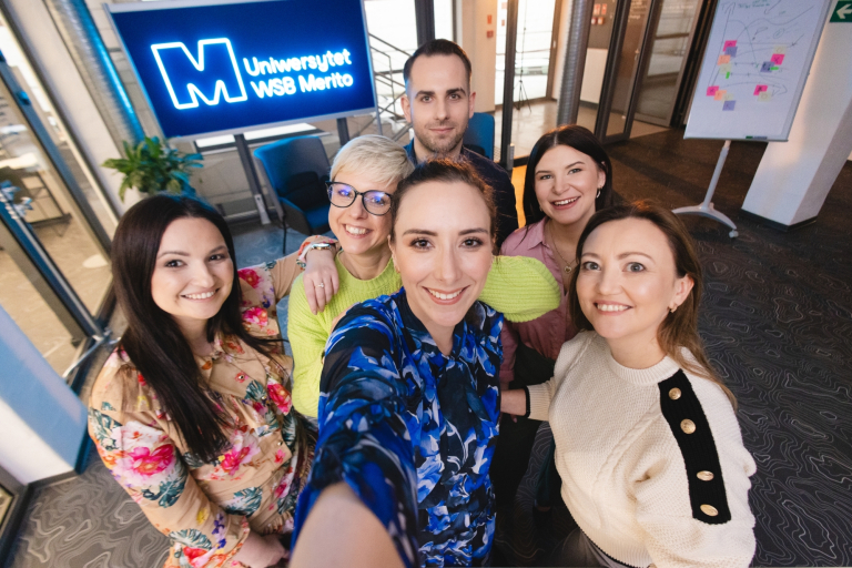 Social media i influencer marketing | Studia podyplomowe w Gdańsku | Uniwersytet WSB Merito w Gdańsku: Selfie słuchaczy studiów podyplomowych przy neonowym sygnecie Merito