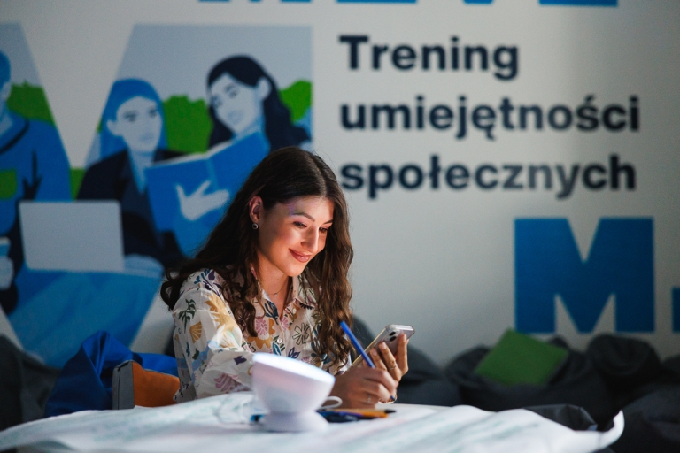 Doradztwo inwestycyjne | Studia II stopnia w Gdańsku | Uniwersytet WSB Merito w Gdańsku: Studentka przy banerze treningu umiejętności społecznych