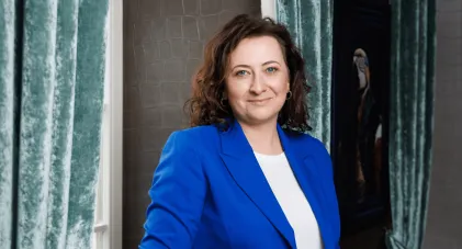 Władze uniwersytetu | Uniwersytet WSB Merito w Gdańsku: Kobieta w kręconych włosach i marynarce w kolorze indygo