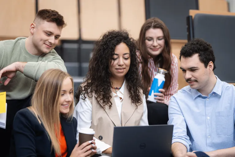 Programowanie desktop apps | Studia II stopnia w Gdańsku | Uniwersytet WSB Merito w Gdańsku: Studenci zebrani wokół laptopa na auli
