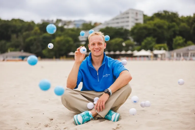 Psychologia w biznesie | Studia II stopnia w Gdańsku | Uniwersytet WSB Merito w Gdańsku: Student siedzi po turecku na plaży, wokół niego latają piłeczki