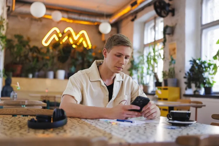 Zarządzanie w administracji publicznej | Studia II stopnia w Gdańsku | Uniwersytet WSB Merito w Gdańsku: Student przy telefonie w kawiarni 