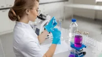 Podologia w praktyce | Studia podyplomowe w Gdyni | Uniwersytet WSB Merito Gdynia: dziewczyna siedząca przy biurku w laboratorium i korzystająca z probówek