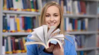 Inżynieria oprogramowania dla technologii kosmicznych | Studia I stopnia w Gdyni | Uniwersytet WSB Merito Gdynia: Studentka w bibliotece z książką