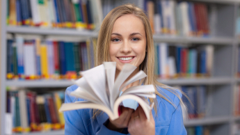 Inżynieria oprogramowania dla technologii kosmicznych | Studia I stopnia w Gdyni | Uniwersytet WSB Merito Gdynia: Studentka w bibliotece z książką