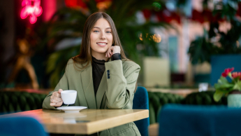 Projektowanie i aranżacja wnętrz | Studia podyplomowe w Gdyni | Uniwersytet WSB Merito Gdynia: Studentka w kawiarni z kawą w ręku 