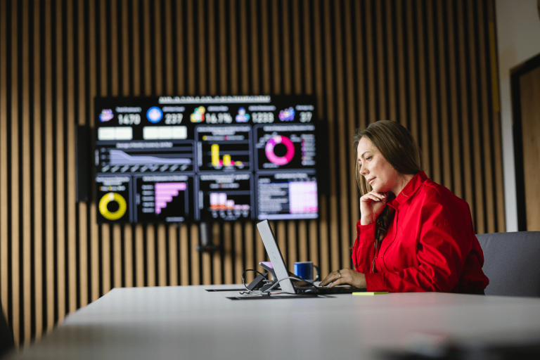 Lean Management z przygotowaniem do certyfikacji Green Belt | Studia podyplomowe w Gdyni | Uniwersytet WSB Merito Gdynia: Kobieta na spotkaniu online, w tle ekran z wykresami