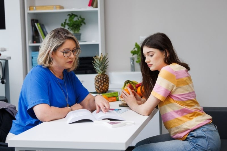 Psychotraumatologia specjalistyczna z elementami psychoterapii | Studia podyplomowe w Gdyni | Uniwersytet WSB Merito Gdynia: Dwie studentki podczas nauki. W tle ananas
