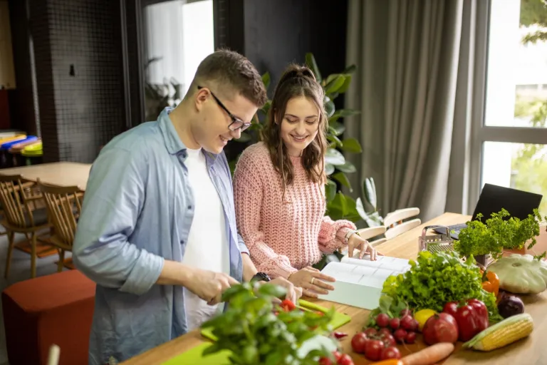 Dietetyka | Studia I stopnia w Gdyni | Uniwersytet WSB Merito Gdynia: Student i studentka nad książką, wokół warzywa i owoce