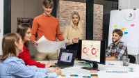 Marketing i sprzedaż | Studia I stopnia w Łodzi | Uniwersytet WSB Merito Łódź: Grupa młodych osób analizuje dane i wykresy podczas zespołowej pracy nad projektem logistycznym w nowoczesnym biurze.