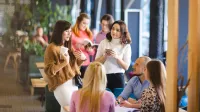Psychologia w biznesie | Studia podyplomowe w Łodzi | Uniwersytet WSB Merito Łódź: Grupa ludzi rozmawia przy stole.