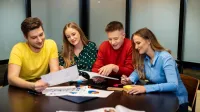 Projektowanie komunikacji produktowej | Studia I stopnia w Łodzi | Uniwersytet WSB Merito Łódź: Czworo studentów uczy się z książek i notatek.