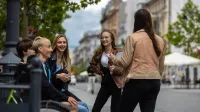 Doradztwo zawodowe i coaching kariery | Studia podyplomowe w Łodzi | Uniwersytet WSB Merito Łódź: Grupka studentów rozmawia śmiejąc się na mieście.