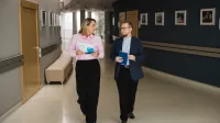 Psychologia polityki i komunikacja w kampaniach wyborczych | Studia podyplomowe w Łodzi | Uniwersytet WSB Merito Łódź: 2 osoby spacerujące po korytarzu mba 