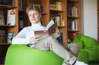 Nasz kampus | Uniwersytet WSB Merito Łódź: Uczeń czyta książkę w bibliotece Uniwersytetu WSB Merito w Łodzi