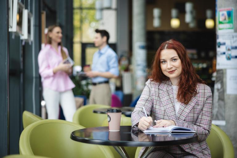 Marketing i sprzedaż | Studia I stopnia w Łodzi | Uniwersytet WSB Merito Łódź: Studentka zapisuje notatki, a obok stoi kawa.