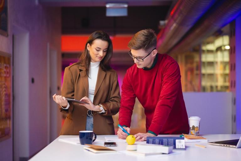 Zarządzanie i inwestowanie w nieruchomości | Studia podyplomowe w Łodzi | Uniwersytet WSB Merito Łódź: Dwoje młodych ludzi pracuje wspólnie przy biurku.